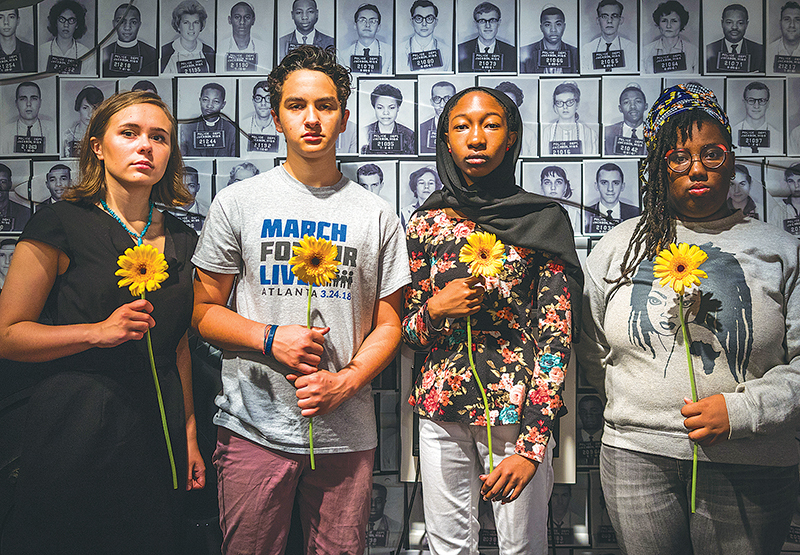 The MFOL 4 pose in front of mugshots of the Freedom Riders who served before them, inside the Center for Civil and Human Rights Museum. Photo by Ian Marceda and Jacob Ross.